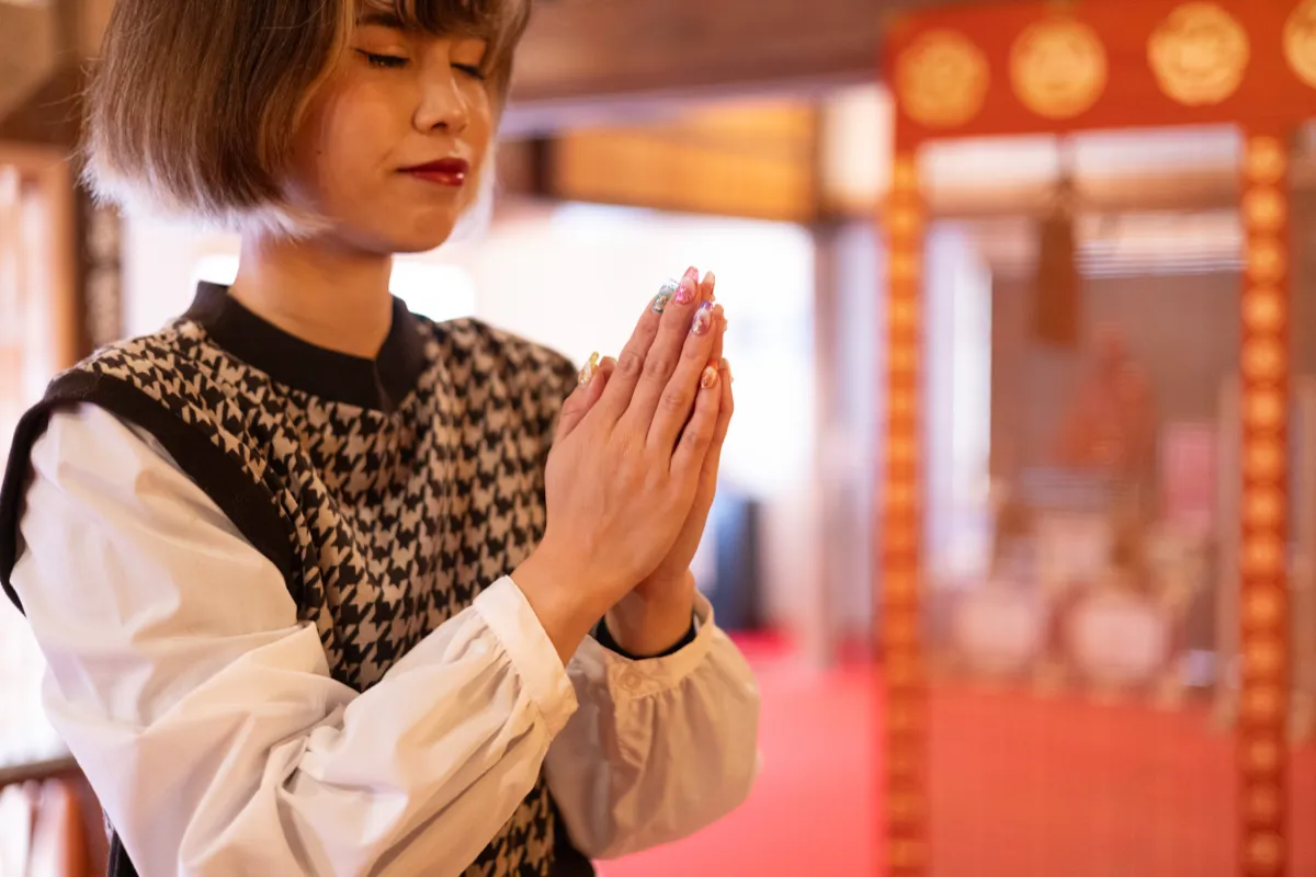 本堂で静かに手を合わせて祈る参拝者